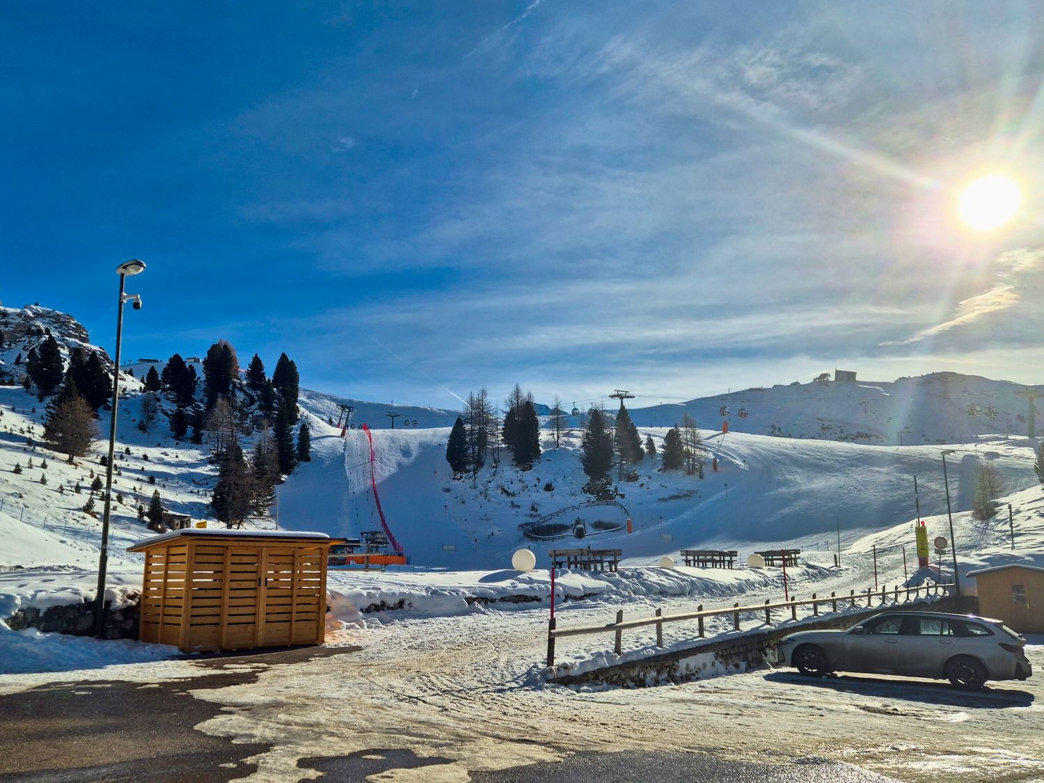 Where to stay in the Dolomites for skiing 5 Snow covered ski slopes in Val di Fassa in December with chairlifts and evergreen trees beneath a bright blue sky. The sunny Dolomites setting shows the clear groomed runs and alpine scenery that make skiing in the Dolomites popular in winter.